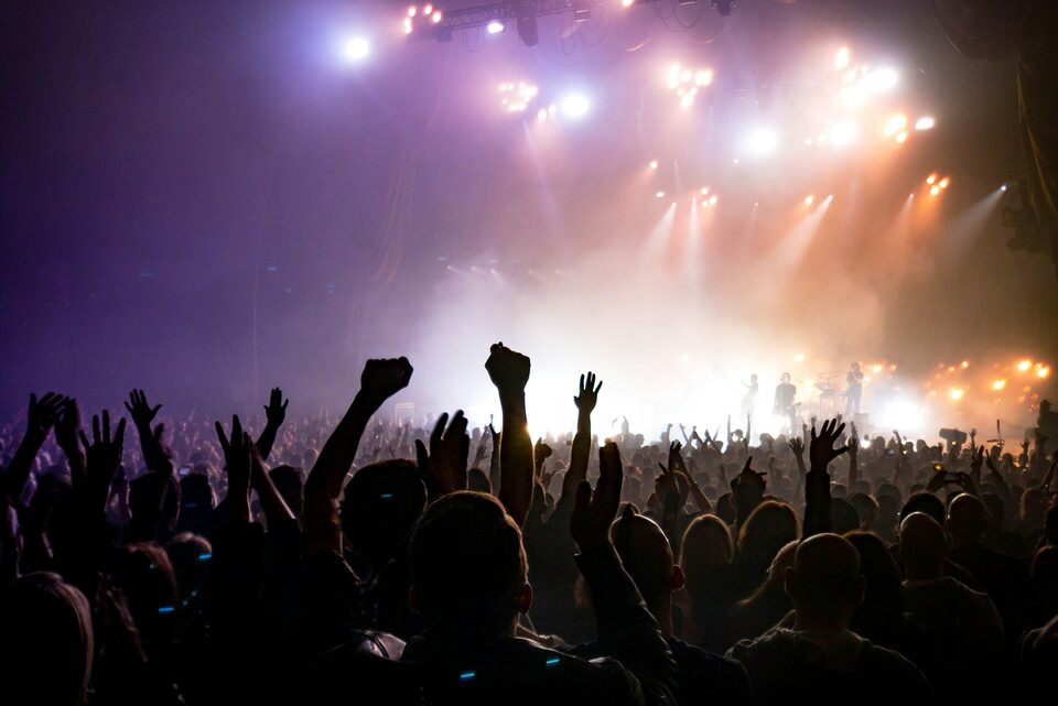 Hands raised in a crowd as the stage lights up